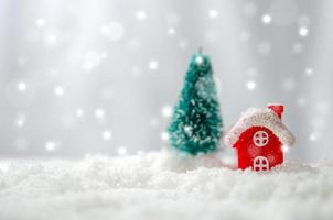 casa ed em miniatura e árvore de natal na neve foto