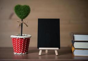 pequeno quadro-negro com plantas em forma de coração e livros foto