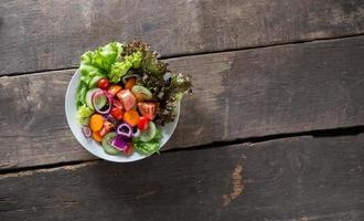 salada de legumes fresca em fundo de madeira foto