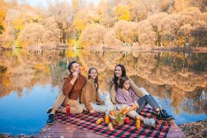 linda família no dia quente de outono perto do lago foto