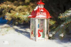 lanterna decorativa de natal perto do ramo de abeto na neve dia de inverno foto