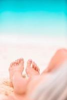 pés de mulher na praia de areia branca em águas rasas foto