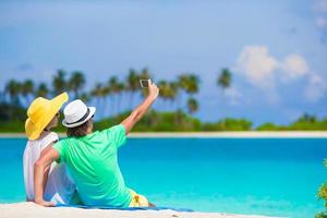 família de dois fazendo uma selfie com celular na praia foto