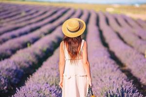 mulher no campo de flores de lavanda em vestido branco e chapéu foto