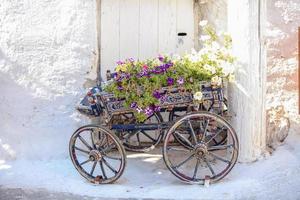 carrinho decorativo encantador com flores na rua na vila de emporio em cyclades, grécia foto