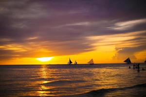 lindo pôr do sol colorido com veleiro no horizonte na ilha de boracay foto