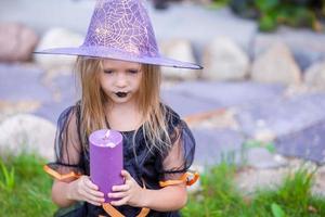 adorável menina vestindo fantasia de bruxa no dia das bruxas no dia de outono. doçura ou travessura. foto