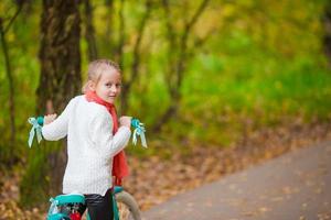 adorável garota andando de bicicleta no lindo dia de outono ao ar livre foto