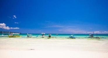 praia de areia tropical perfeita com água azul-turquesa e pequenos veleiros foto