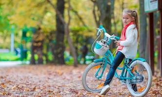 adorável garota andando de bicicleta no lindo dia de outono ao ar livre foto