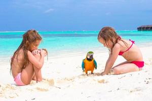 adoráveis meninas com grande papagaio colorido durante as férias na praia foto