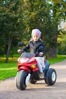 menina adorável se divertindo em sua motocicleta de brinquedo foto