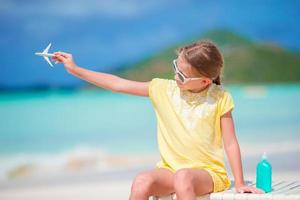 menina feliz com avião de brinquedo nas mãos na praia de areia branca. foto