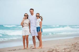 jovem pai e suas adoráveis filhas adolescentes na praia. férias com a família foto