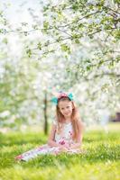 menina adorável no jardim de maçã florescendo em lindo dia de primavera foto