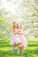 adoráveis meninas no jardim de macieiras florescendo na primavera foto