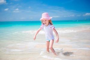 adorável menina na praia se divertindo muito em águas rasas foto