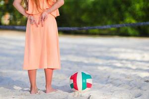 menina adorável jogando vôlei na praia com bola foto