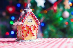 casa de fada de gengibre em um fundo de árvore de natal brilhante com guirlanda foto