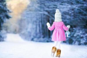 menina adorável com lanterna e vela no inverno na véspera de natal ao ar livre foto