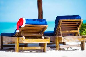 chapéu de Papai Noel na espreguiçadeira de praia. conceito de férias de natal foto