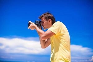 close-up de jovem com uma câmera na praia de areia branca foto