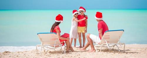 família feliz com dois filhos com chapéu de Papai Noel nas férias de verão foto