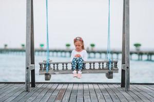 adorável menina em balanço ao pôr do sol foto