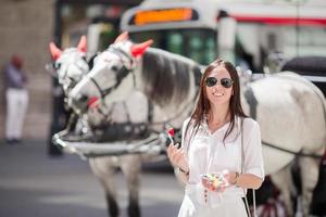 menina turista aproveitando as férias em viena e olhando para os belos cavalos na carruagem foto