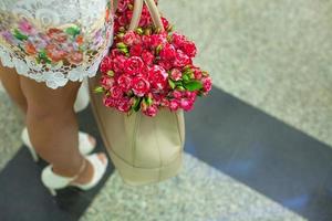 pequenas rosas vermelhas charmosas na bolsa feminina da moda foto