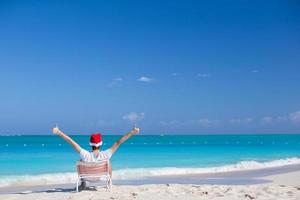jovem de chapéu de Papai Noel durante as férias na praia foto