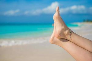 close-up de pés femininos na praia de areia branca foto