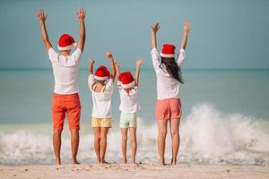 família feliz com dois filhos com chapéu de Papai Noel nas férias de verão foto