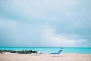 espreguiçadeiras brancas em uma bela praia tropical nas maldivas foto