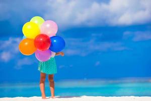 adorável menina brincando com balões na praia foto