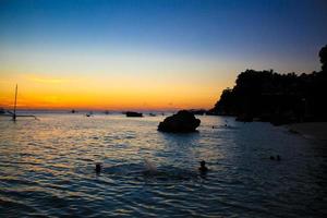 lindo pôr do sol colorido com veleiro no horizonte na ilha de boracay foto