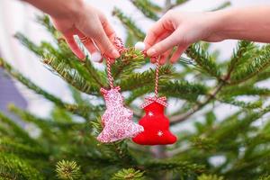 close-up de uma mão decorando os tradicionais enfeites de árvore de natal foto