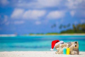 acessórios de praia com chapéu de Papai Noel na praia tropical branca foto