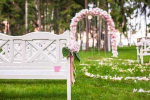 bancos de casamento e arco de flores para cerimônia ao ar livre foto