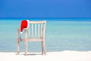 chapéu de papai noel vermelho na cadeira de praia em férias tropicais foto