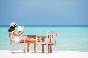 jovem lendo livro durante a praia branca tropical foto