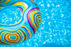anel de borracha inflável colorido flutuando na piscina azul foto