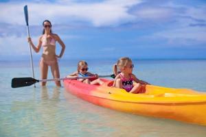 jovem mãe e duas filhas pequenas andando de caiaque no mar quente tropical foto