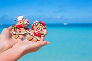 biscoitos de gengibre de natal nas mãos contra o mar turquesa foto