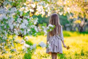 menina adorável no jardim de macieiras florescendo na primavera foto