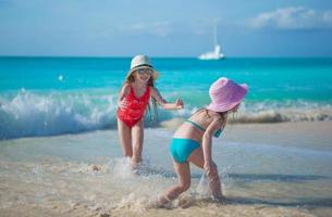 adoráveis garotinhas brincando em águas rasas em uma praia exótica foto