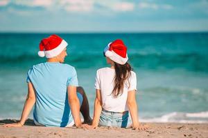 casal feliz de natal em chapéus de papai noel nas férias na praia foto