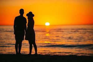 casal romântico na praia ao pôr do sol colorido no fundo foto