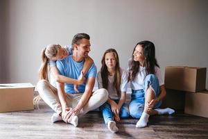 família feliz com duas filhas se divertem em sua nova casa. pais com filhos aproveitam o dia da mudança foto