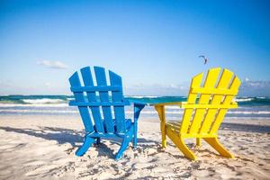 duas cadeiras de madeira, amarelas e azuis em uma praia de areia branca, méxico foto